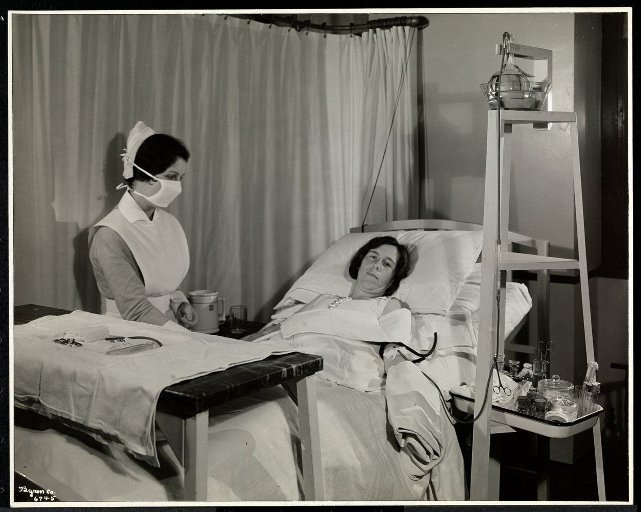 A masked nurse with a patient in a room at the Sloane Medical Hospital, New York, 1932 by Byron Company