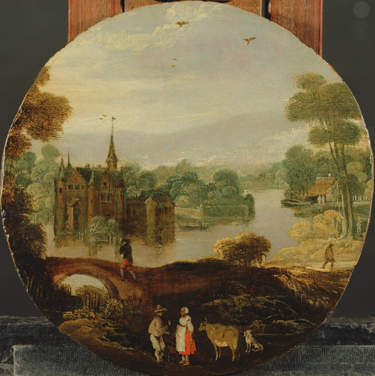 A wooded river landscape with a castle and travellers conversing by Tobias Verhaecht