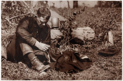 Tramp repairing his clothes by . .